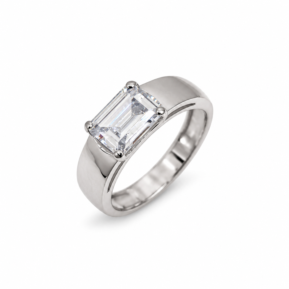 Silver ring with an emerald-cut clear solitaire stone and wide polished band.