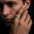 Silver ring with a round clear centre stone, square setting and pavé-set shoulders.
