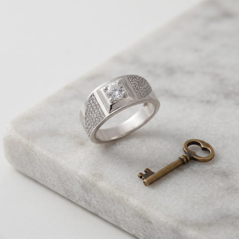 Silver ring with a round clear centre stone, square setting and pavé-set shoulders.