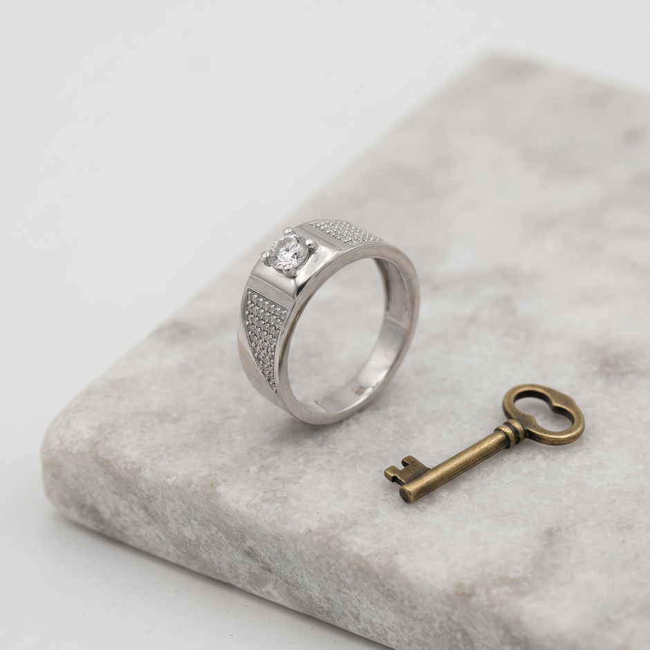 Silver ring with a round clear centre stone, square setting and pavé-set shoulders.