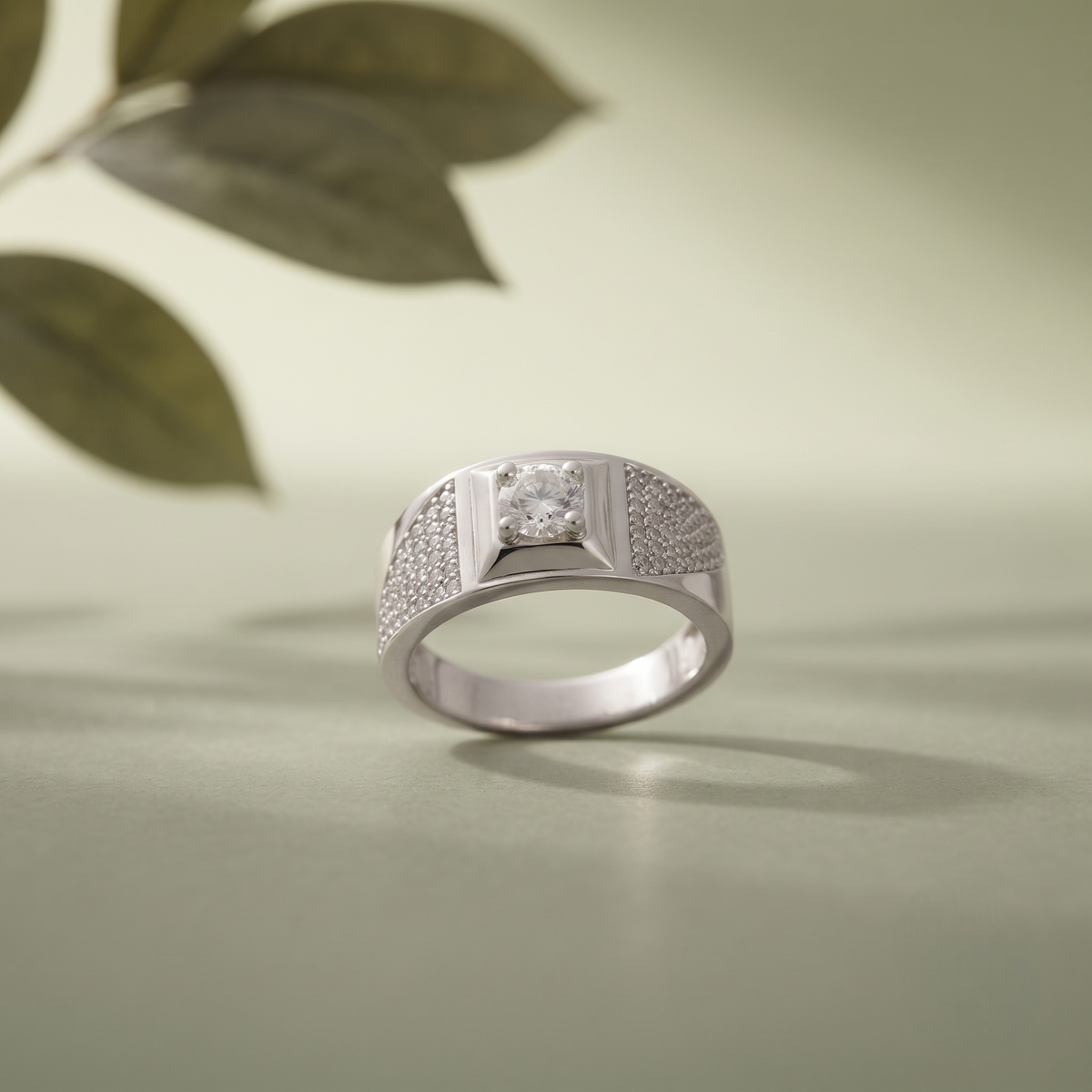 Silver ring with a round clear centre stone, square setting and pavé-set shoulders.