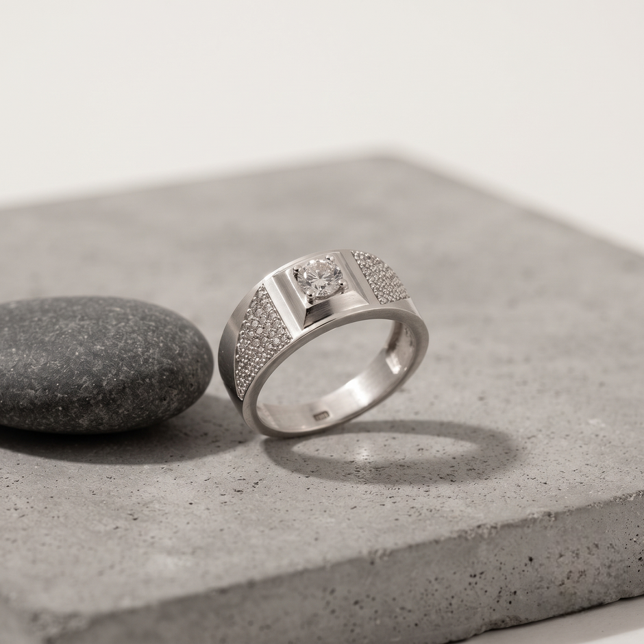 Silver ring with a round clear centre stone, square setting and pavé-set shoulders.