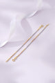 Two gold bracelets on a soft white fabric background