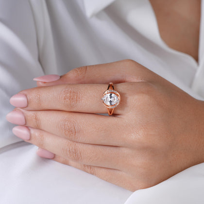 Rose gold ring with a diamond on a hand against a white background