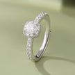 925 sterling silver halo engagement ring with a round brilliant-cut center stone and pavé band, worn on a woman's hand against a soft white background.