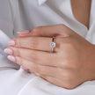 925 sterling silver solitaire ring with a round brilliant-cut stone, worn on a woman's hand against a soft white fabric background.