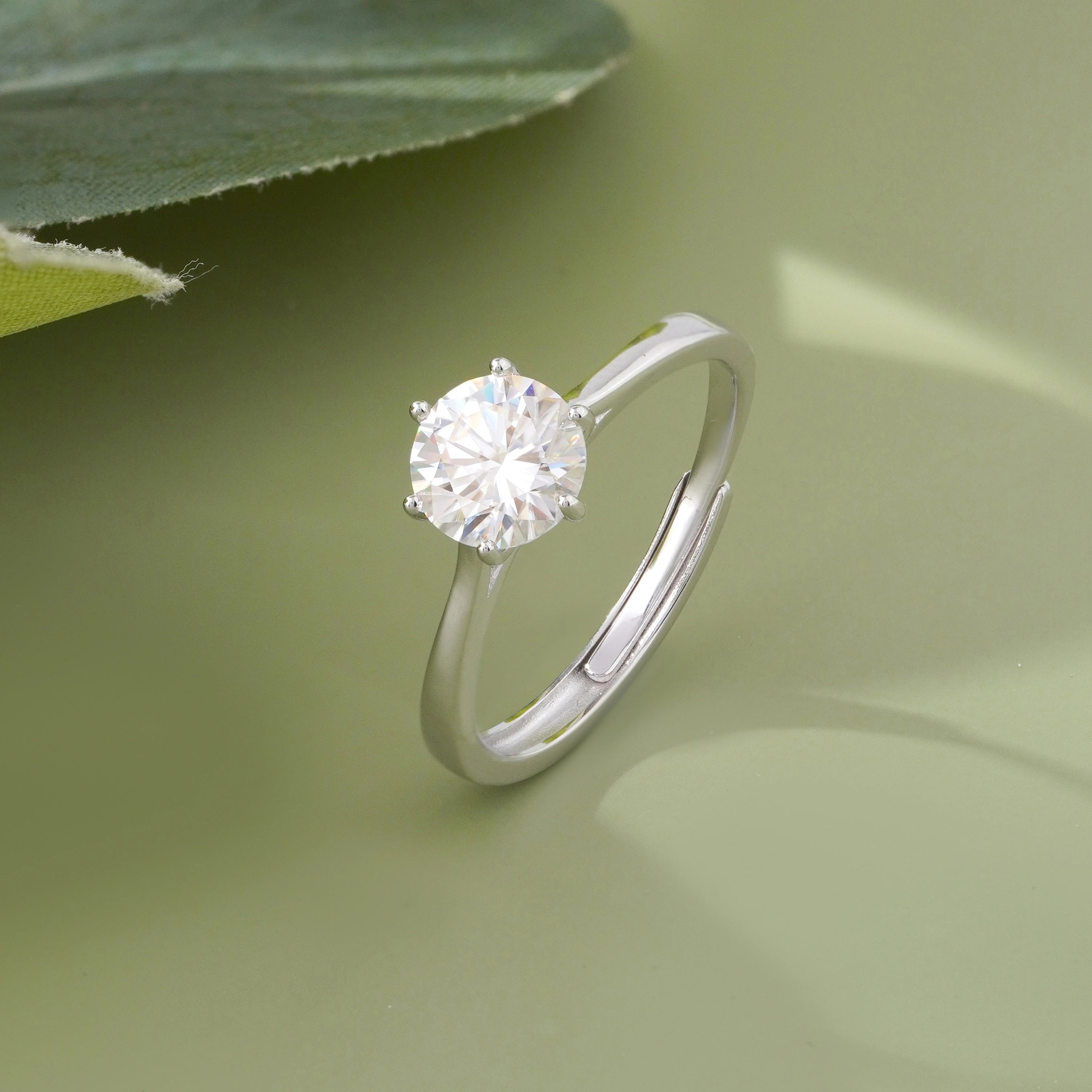 925 sterling silver solitaire ring with a round brilliant-cut stone, worn on a woman's hand against a soft white fabric background.