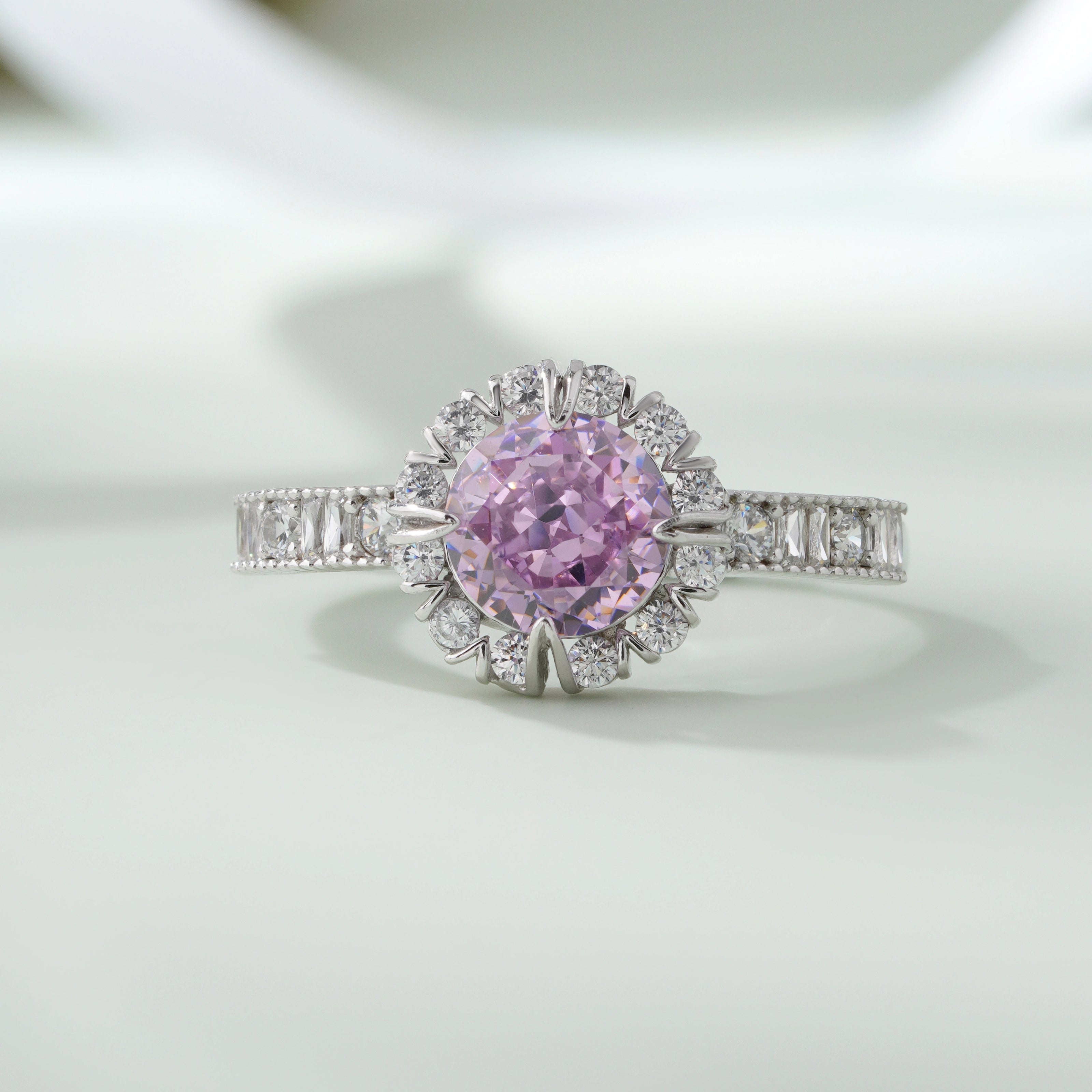 Ring with a pink diamond and diamond halo on a light background
