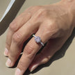 Close-up of a hand wearing a pink gemstone ring with a soft pink background