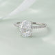 Diamond ring with a pear-shaped center stone on a light green background